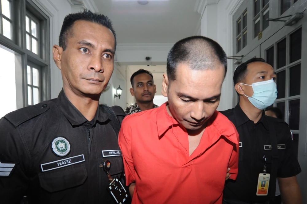 Rosmaini Abd Raof is escorted by police officers to the Johor Baru High Court February 7, 2025, where he filed an application to suspend his 10-year prison sentence. — Picture by Ben Tan