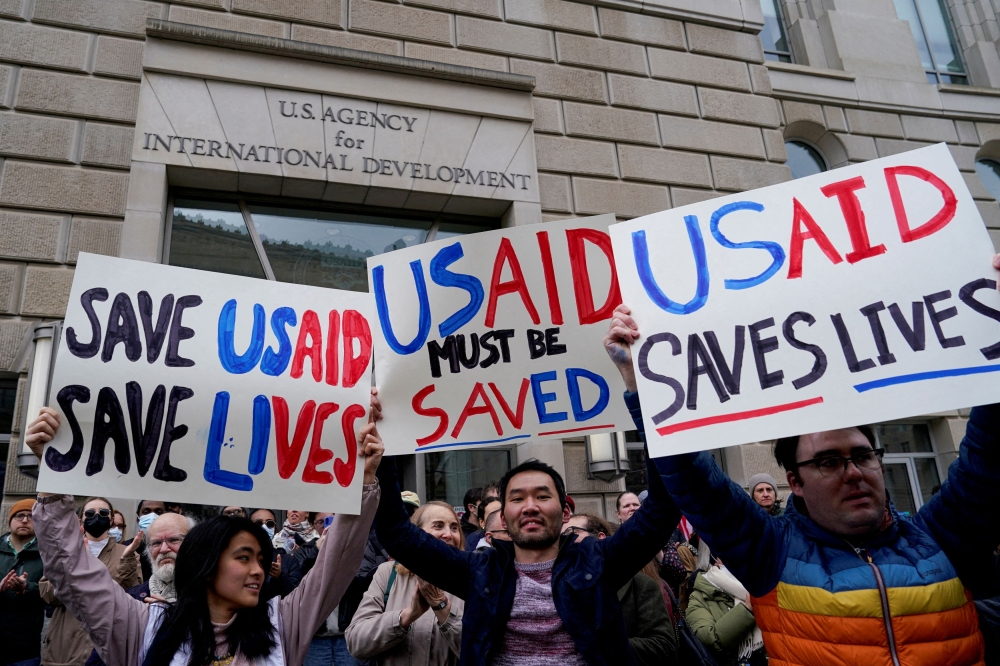 People hold placards as the USAID building sits closed to employees after a memo was issued advising agency personnel to work remotely, in Washington, D.C. February 3, 2025. — Reuters pic  