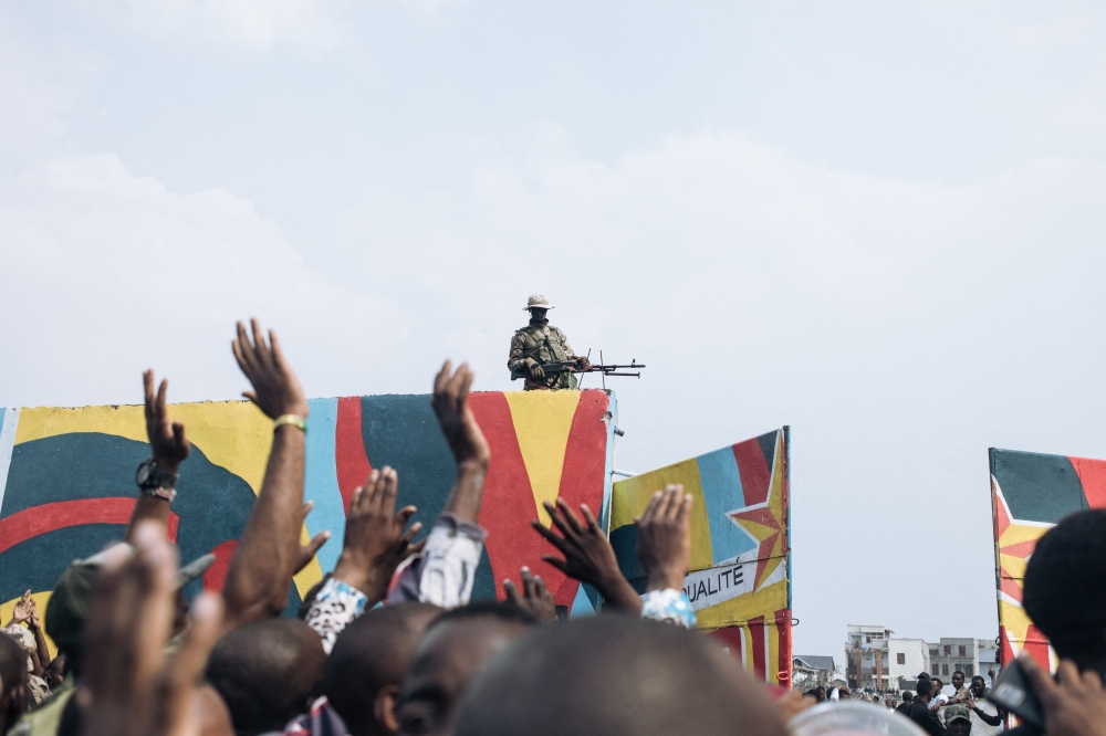 Residents in the Democratic Republic of the Congo raise their hands as a rebel soldier monitors access to Unity Stadium in Goma on February 6, 2025 after rebel M23 and Rwandan forces claimed control on January 27. — AFP pic