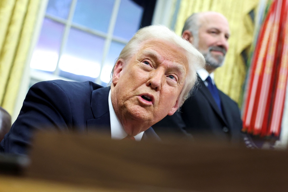 US President Donald Trump speaks, while Howard Lutnick stands in the background, in the Oval Office of the White House in Washington February 10, 2025. — Reuters pic  