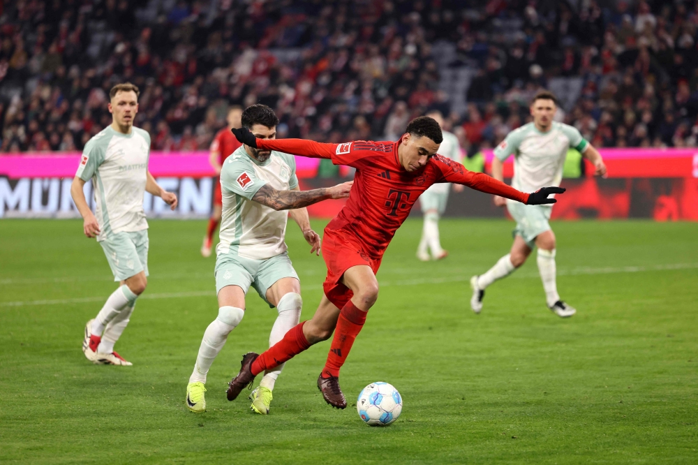 Bayern Munich's German midfielder #42 Jamal Musiala (right) is fauled during the German first division Bundesliga football match FC Bayern Munich vs SV Werder Bremen in Munich, southern Germany on February 7, 2025. — AFP pic