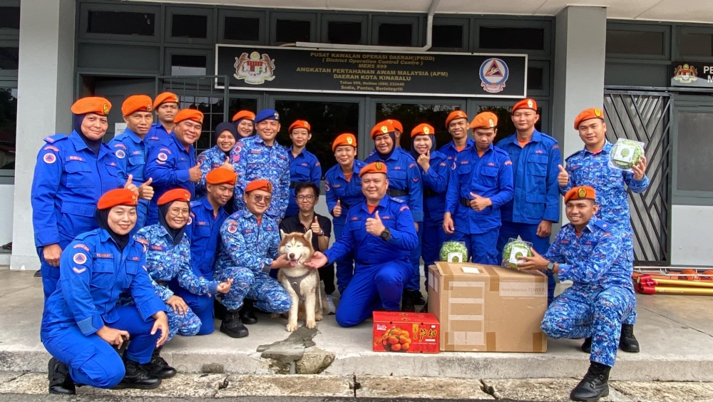Husky Sky posing with the Civil Defence Force and its owner. — Picture via Facebook/Kota Kinabalu Civil Defence Force