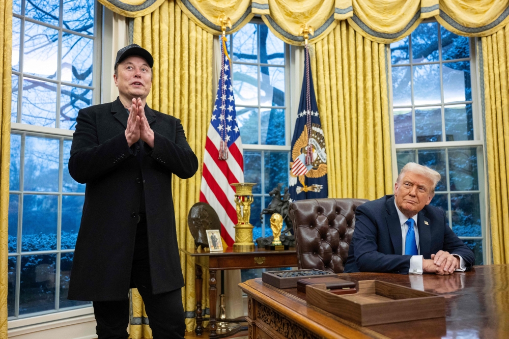 Elon Musk (left) speaks as US President Donald Trump looks on in the Oval Office of the White House in Washington, DC, on February 11, 2025. — AFP pic