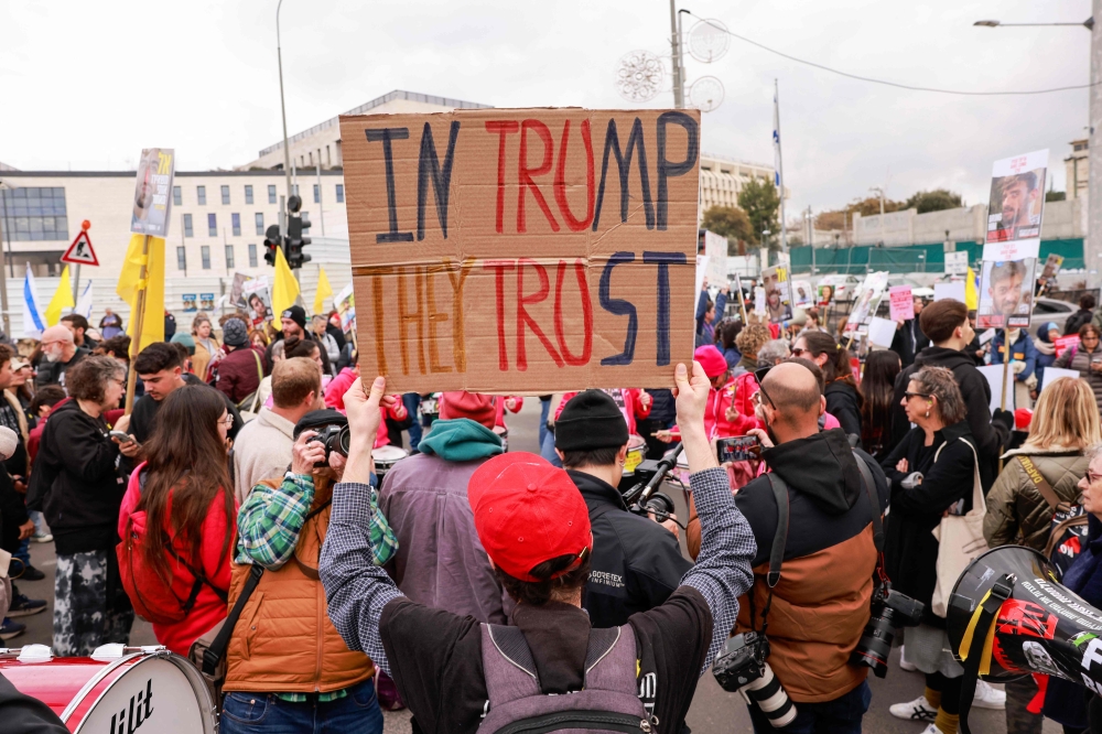 Supporters of Israelis lift placards and flags in front of the prime minister’s office in Jerusalem on February 11, 2025. — AFP pic