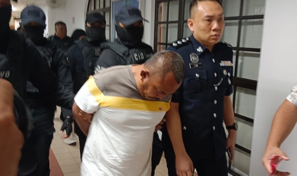 The accused, Zuraidi Zakaria, is escorted by police to the Johor Baru Magistrate’s Court February 12, 2025, where he was charged with the murder of his 79-year-old mother-in-law. — Picture by Ben Tan