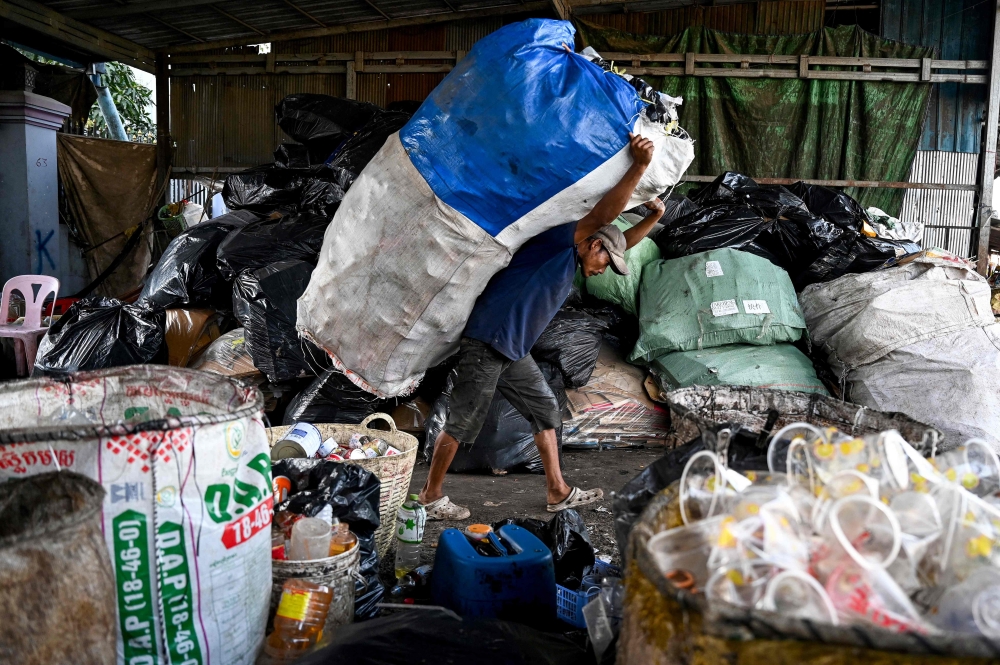 This photo taken on January 30, 2025 shows a worker carrying a bag containing plastic bottles at a recycling depot on the outskirts of Phnom Penh. — AFP pic