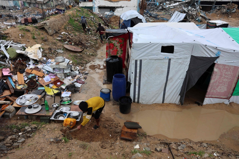 A Palestinian man clears the mud in front of a tent during the rainy season in Beit Hanun in the northern Gaza Strip on February 12, 2025. — AFP pic