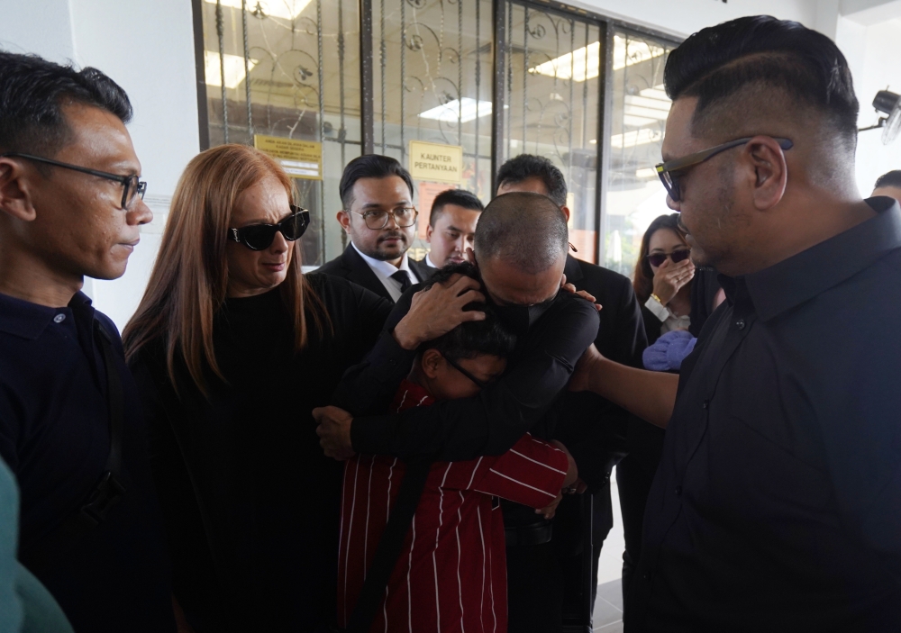 Actor and comedian Muhammad Nizamuddin Ahmad, better known as Along Cham, hugs his child after the Sessions Court today granted him a discharge not amounting to an acquittal (DNAA) on a charge of possessing cannabis in Sepang, January 27, 2025. Previously, Along, or Muhammad Nizamudin Ahmad, 42, accused his wife, Afreena Suhaimi, of misappropriating hundreds of thousands of ringgit in public donations that were meant to support him while he was detained at Sungai Buloh Prison on charges of cannabis possession. — Bernama pic