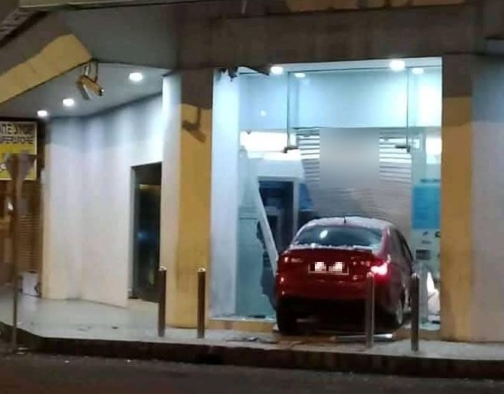 The car lodged in the glass door of the RHB Bank branch on Jalan Mahkamah in Tawau. — Picture via Facebook