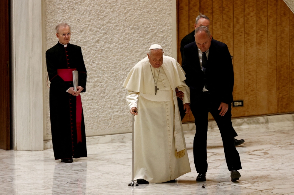 Pope Francis is helped by his aide after a part of his cane broke off during his arrival to hold the Jubilee audience in Paul VI Hall at the Vatican, February 1, 2025. — Reuters pic
