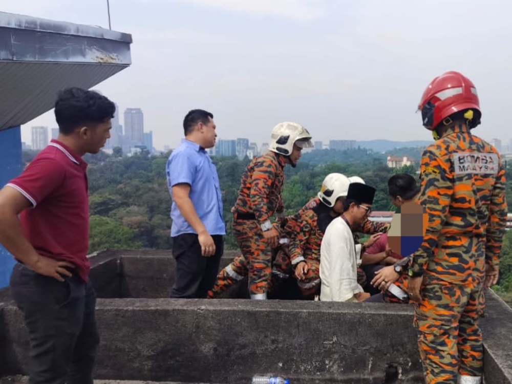 Ajak Shiro (in white) with assistance from fire department personnel, attempts to calm the man during the incident at the LPP building yesterday. — Picture via Facebook