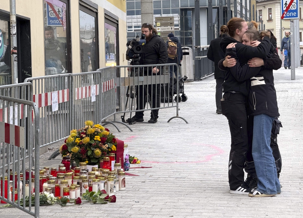 People mourn on February 16, 2025 at a makeshift memorial of candles and flowers placed at the site where a man randomly attacked passers-by with a knife and stabbed to death a teenager and wounded five other people in Villach, Austria. A 23-year-old Syrian asylum seeker was arrested after the stabbing on February 15, 2025. — AFP pic
