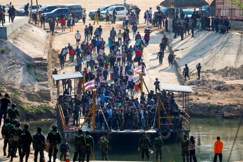 Multinational victims of scam centres, who were tricked or trafficked into working in Myanmar, walk towards a vessel in order to cross Moei River to Thailand, in Phop Phra District, Tak province, Thailand February 12, 2025. — Reuters pic 