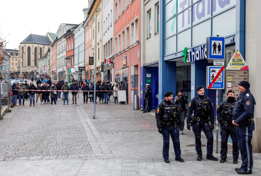Police officers stand guard at the scene where a 14-year-old boy was killed and several others were wounded in a stabbing attack in Villach. — Reuters pic