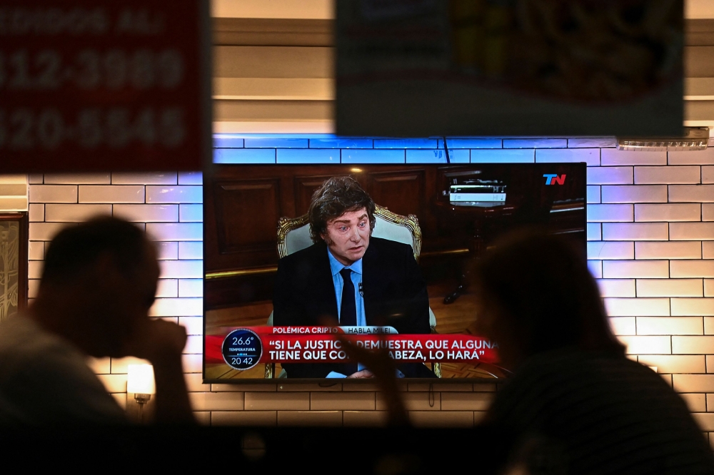 People sit in a restaurant as Argentina’s President Javier Milei is seen on television during an interview, in Buenos Aires, Argentina, February 17, 2025. — Reuters pic 