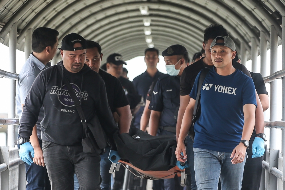 Police personnel carry the body of the suspect in last week's shooting at a Setia Alam shopping mall, who was killed in a police shootout earlier, Klang Port Jetty on February 18, 2025. — Picture by Yusof Mat Isa