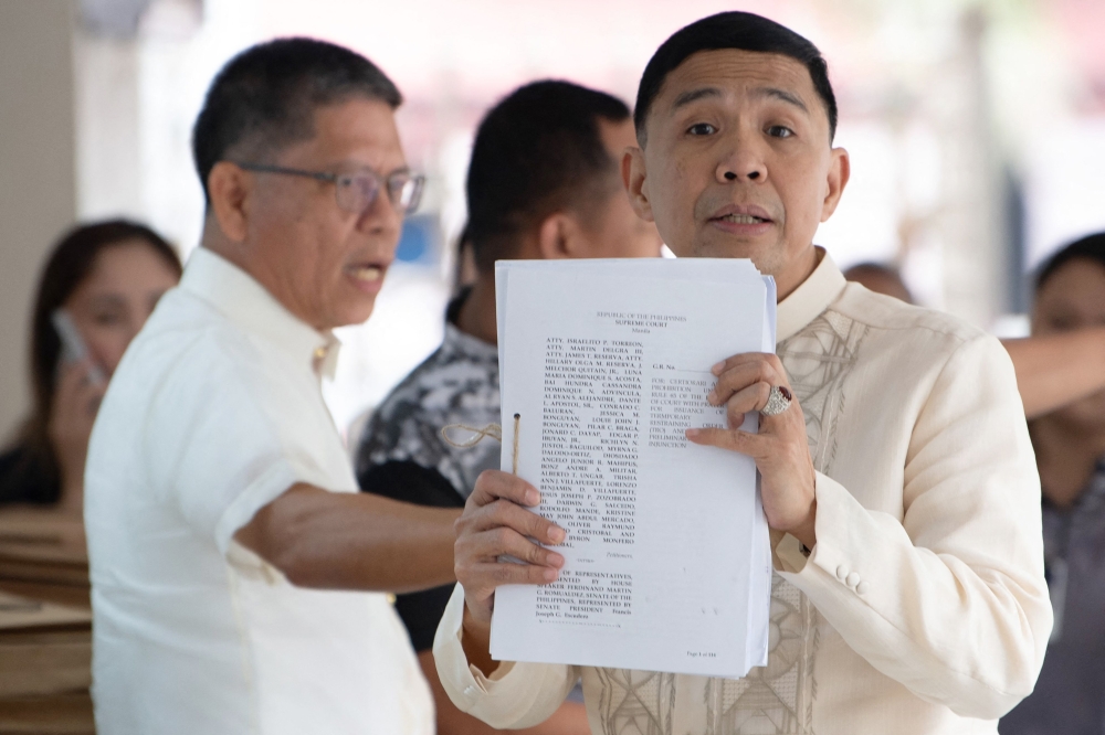 Israelito Torreon (right), who is in support of impeached Philippine Vice-President Sara Duterte, holds up documents after filing a legal challenge against her impeachment at the Supreme Court in Manila on February 18, 2025. — AFP pic 