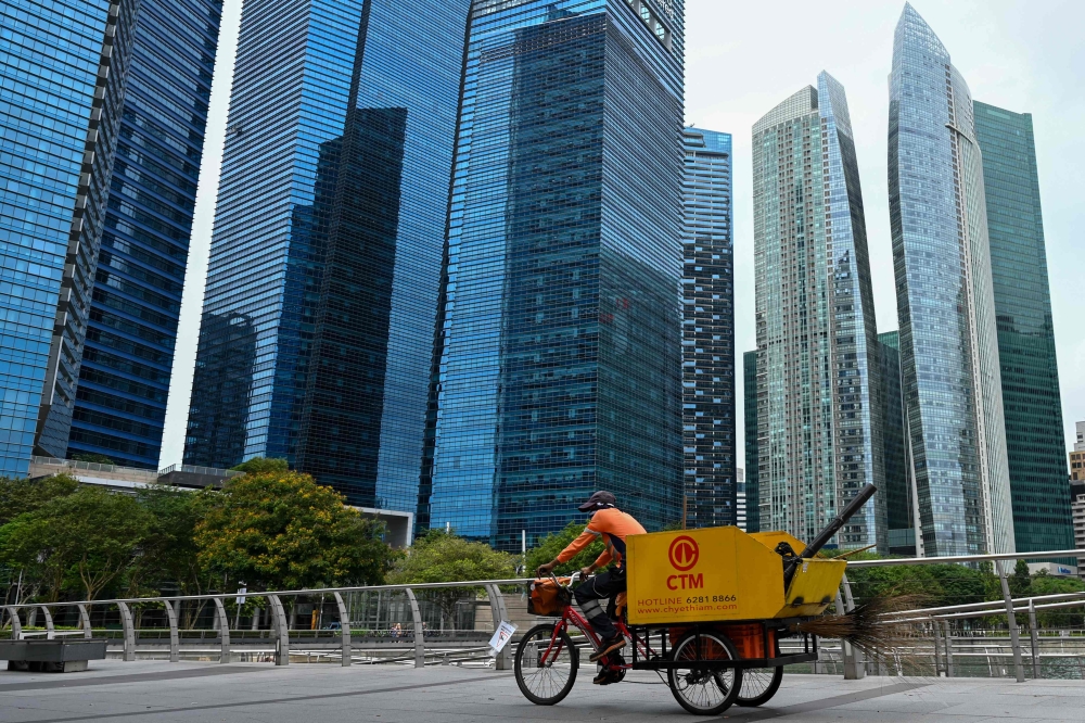 A cleaner on a tricycle rides along the promenade at Marina Bay in Singapore on February 18, 2025. — AFP pic 