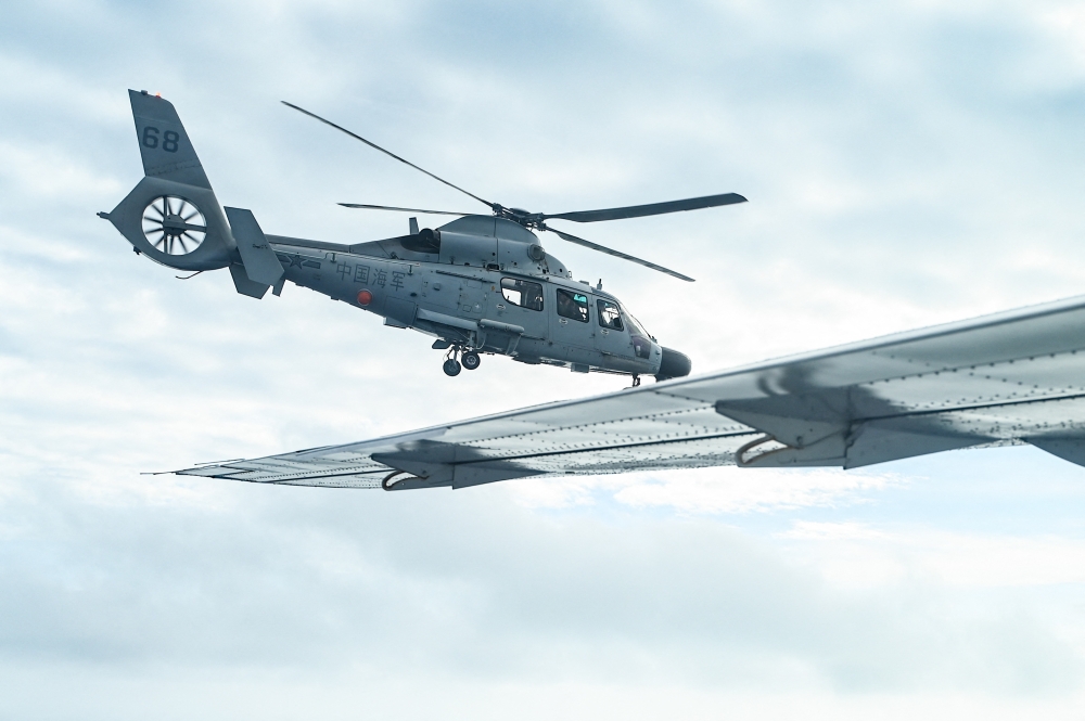 An aircraft identified by the Philippine Coast Guard as Chinese Navy helicopter (left) flies near the Bureau of Fisheries and Aquatic Resources (BFAR) plane during an aerial reconnaissance flight at Scarborough Shoal in the South China Sea on February 18, 2025. — AFP pic