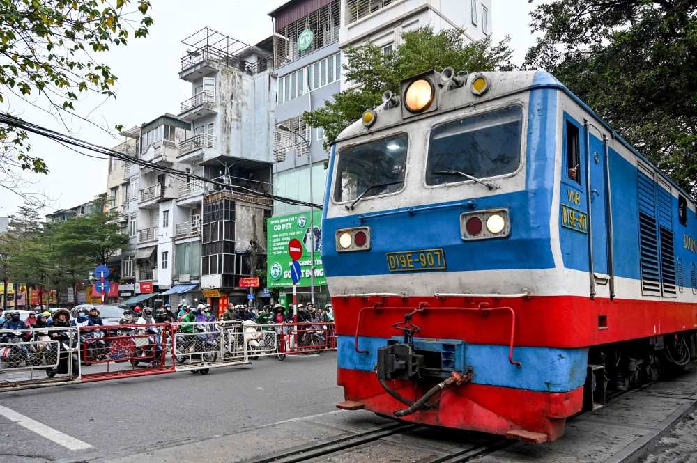Vehicles wait as a train passes at a railway crossing in Hanoi. – Pic by AFP