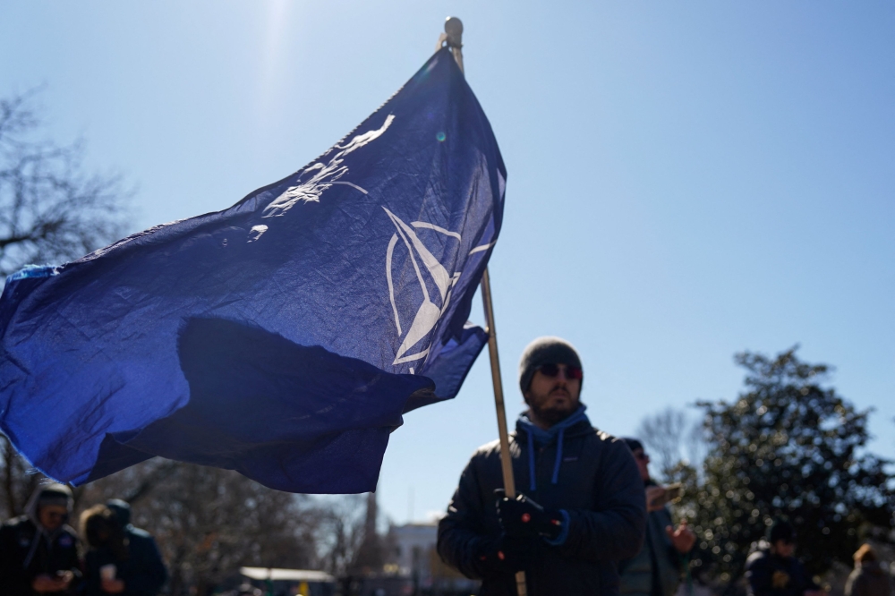 A person waves a Nato flag during a protest outside the White House on President's Day in Washington February 17, 2025. — Reuters pic