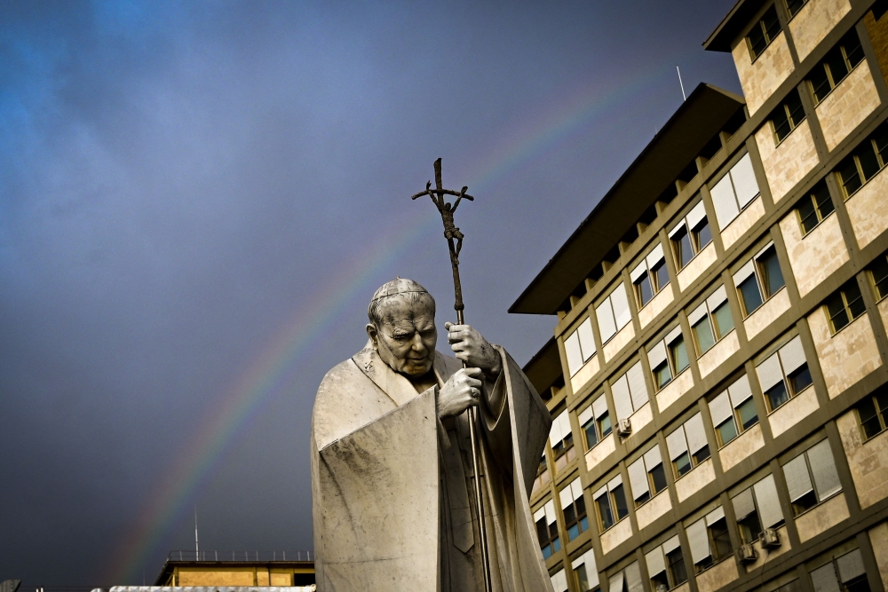 A rainbow appears above a statue of Pope John Paul II outside the Gemelli hospital where Pope Francis is hospitalised for tests and treatment for bronchitis in Rome, on February 18, 2025. — AFP pic
