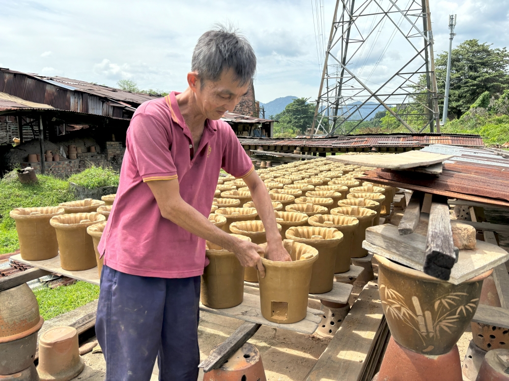 Traditional red clay stove maker Foong Cheah Thong inspects earthen stoves at his factory in Taman Milee, Ipoh. — Picture by John Bunyan
