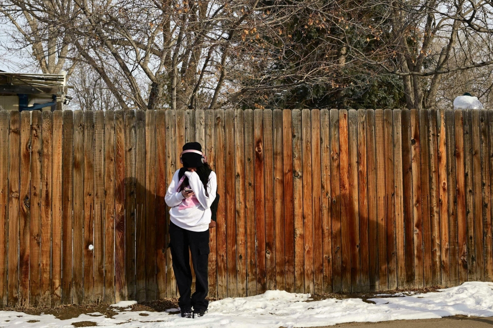 A high school student huddles with her smartphone during below-freezing temperatures in Lafayette, Colorado, U.S. February 19, 2025. — Reuters pic