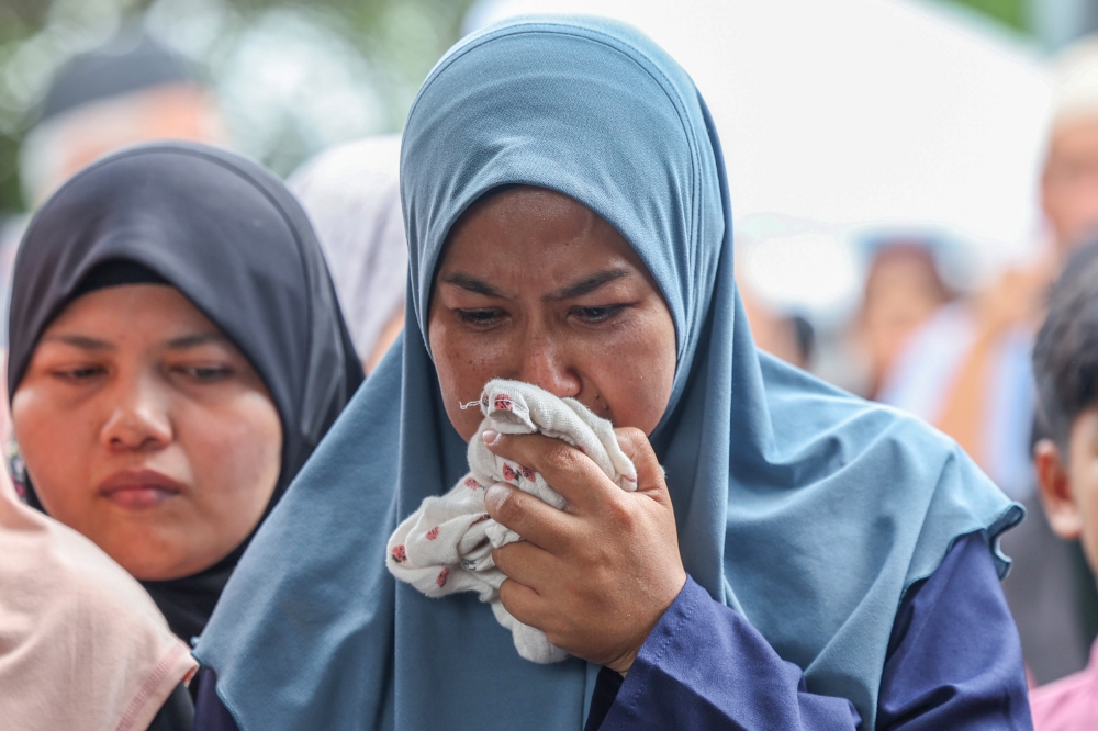 Nuraini Mohamad Isa, 37, at the burial of her son, the late Mohammad Fahmi Hafiz Mohammad Fakhruddin, at the Kampung Permatang Binjai Muslim Cemetery today. — Bernama pic