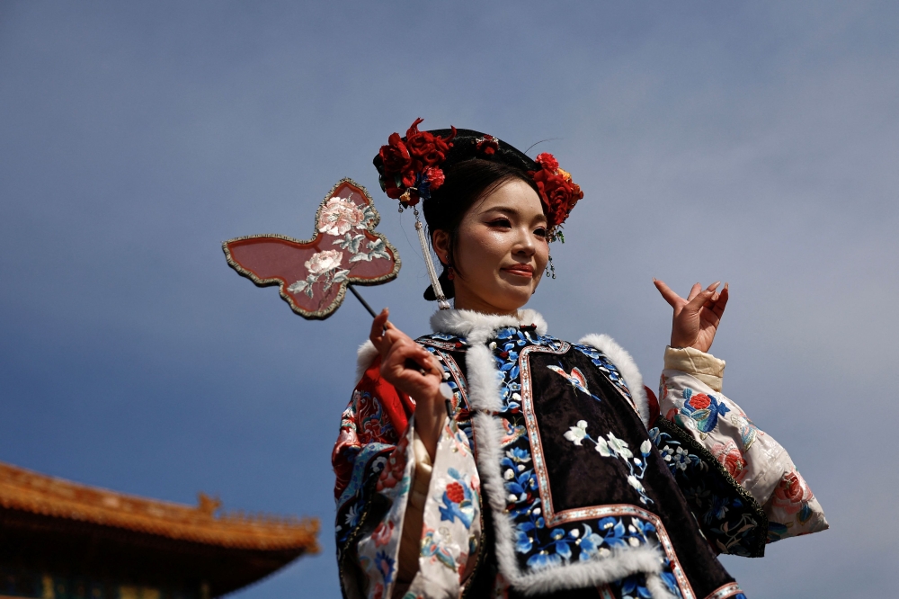 A woman dressed up in a Chinese traditional costume poses for pictures at the Forbidden City in Beijing. — Reuters pic
