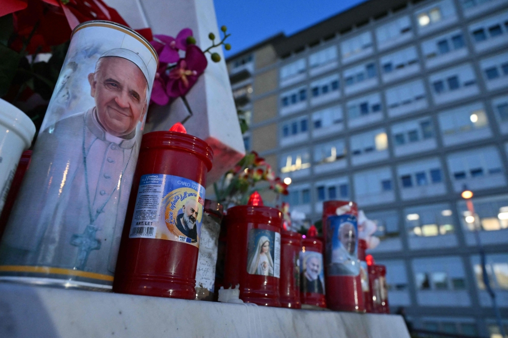 Candles were laid at the statue of John Paul II outside the Gemelli Hospital where Pope Francis is hospitalised in Rome yesterday. — AFP pic