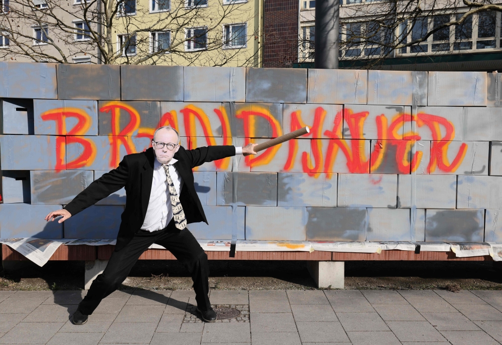 An activist wearing a mask of Leader of Germany's Christian Democratic Union (CDU) Friedrich Merz poses in front of a mock fire wall ahead the final campaign event of Germany's Christian Democratic Union party in Munich. — Pic by AFP