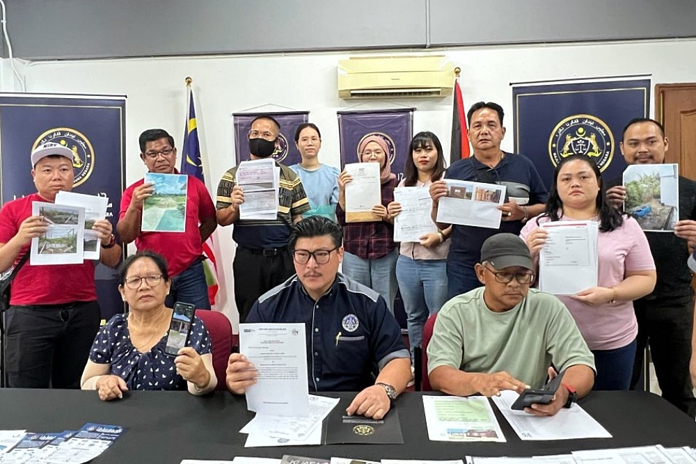 Lau (seated centre) with the cheated victims who lost a collective total of RM1.8 million. — The Borneo Post pic