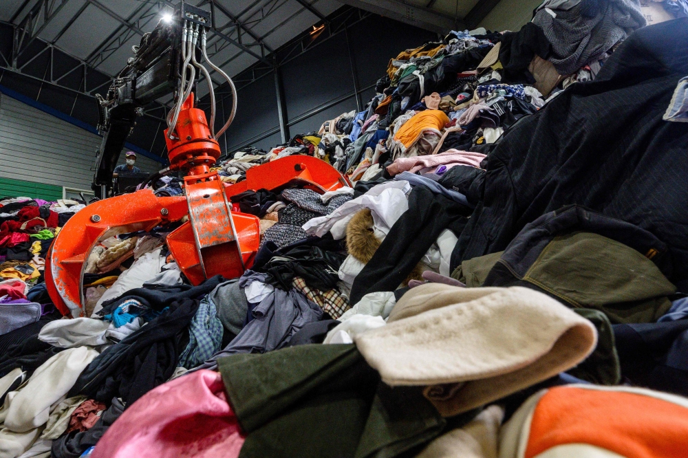 In this photo taken on August 7, 2024, an employee controls a mechanical claw as he helps categorise a huge pile of garments, bedding, accessories and soft toys before they are exported overseas. — AFP pic