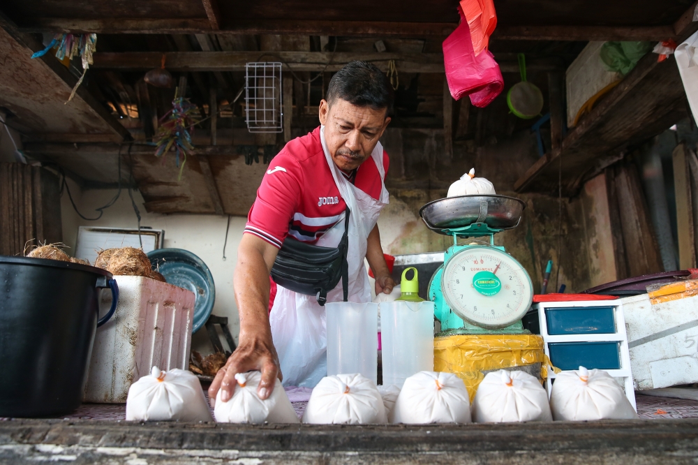 Mohd Nordin Katmin, 59, arranges coconut milk for sales at his stall at Pasar Datuk Keramat in Kuala Lumpur on February 20, 2025. — Picture by Yusof Mat Isa