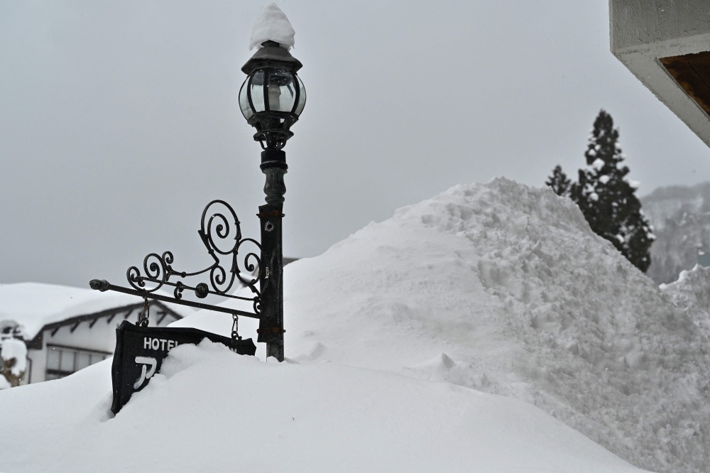 This photo taken on January 31, 2025 shows a sign for a hotel buried amongst snow piled high, along a street in the ski resort town of Hakuba, Nagano prefecture. Residents of northern Japan were sheltering from deep snow up to the rooftops in some areas on February 20 after a two-week whiteout. Several cities have seen record snowfall in February, causing traffic disruption and several fatalities. — AFP pic