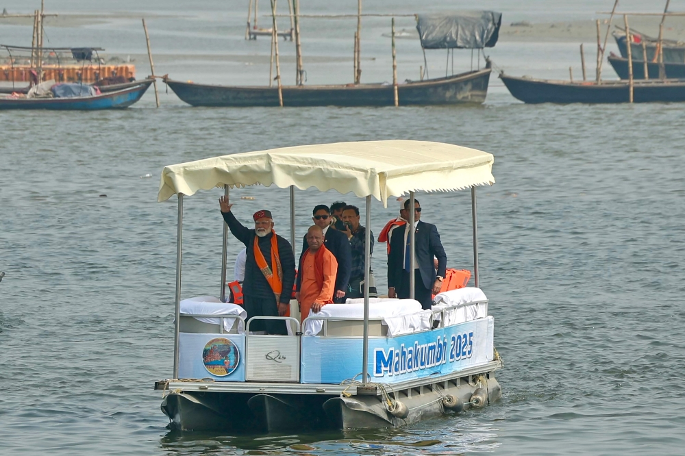 India’s Prime Minister Narendra Modi (centre) waves next to the chief minister of Uttar Pradesh state Yogi Adityanath, from a boat after taking a holy dip in the sacred waters of Sangam, the confluence of Ganges, Yamuna and mythical Saraswati rivers during Maha Kumbh Mela festival, in Prayagraj on February 5, 2025. — AFP pic 