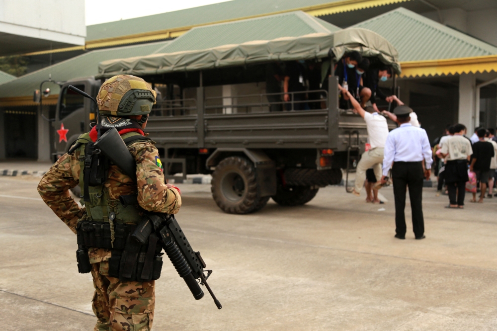 A member of the Karen Border Guard Force (BGF) stands guard next to alleged scam centre workers and victims from China arriving at the border checkpoint with Thailand in Myanmar's eastern Myawaddy township on February 20, 2025. — AFP pic