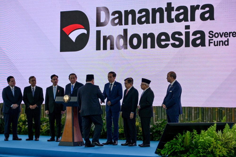 Indonesia’s President Prabowo Subianto (centre) shakes hands with former president Joko Widodo during the launch of a sovereign wealth fund known as Daya Anagata Nusantara, or Danantara, in Jakarta on February 24, 2025. — AFP pic 