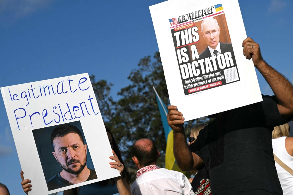 Members of the Ukrainian community in Australia hold placards showing Ukraine's President Volodymyr Zelensky (L) and Russia's President Vladimir Putin (R) during a vigil in central Sydney yesterday. — AFP pic