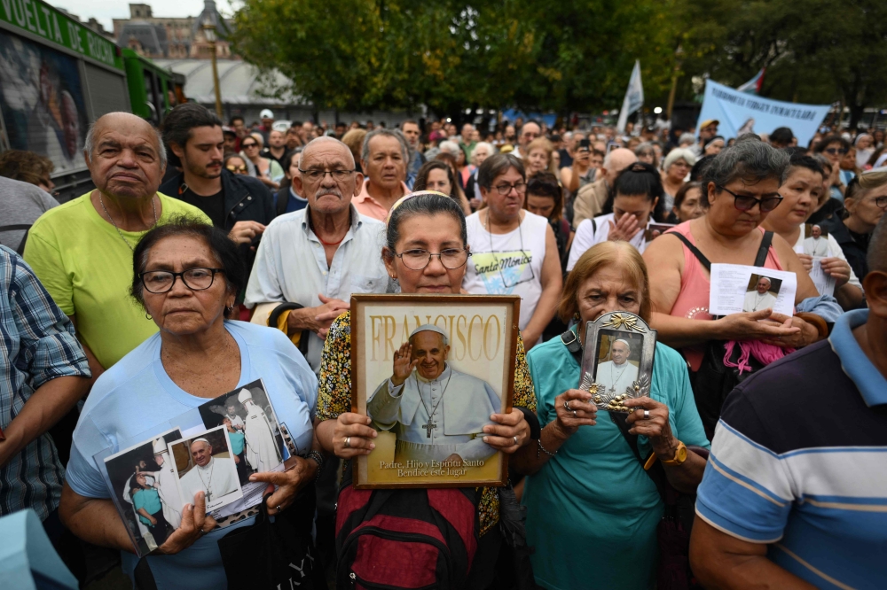 Faithful Catholics hold portraits of Pope Francis as they attend a mass for his healing in Constitution Square, the place where, when he was archbishop of Buenos Aires he gave annual masses to denounce exclusion and human trafficking in Buenos Aires. — Pic by AFP