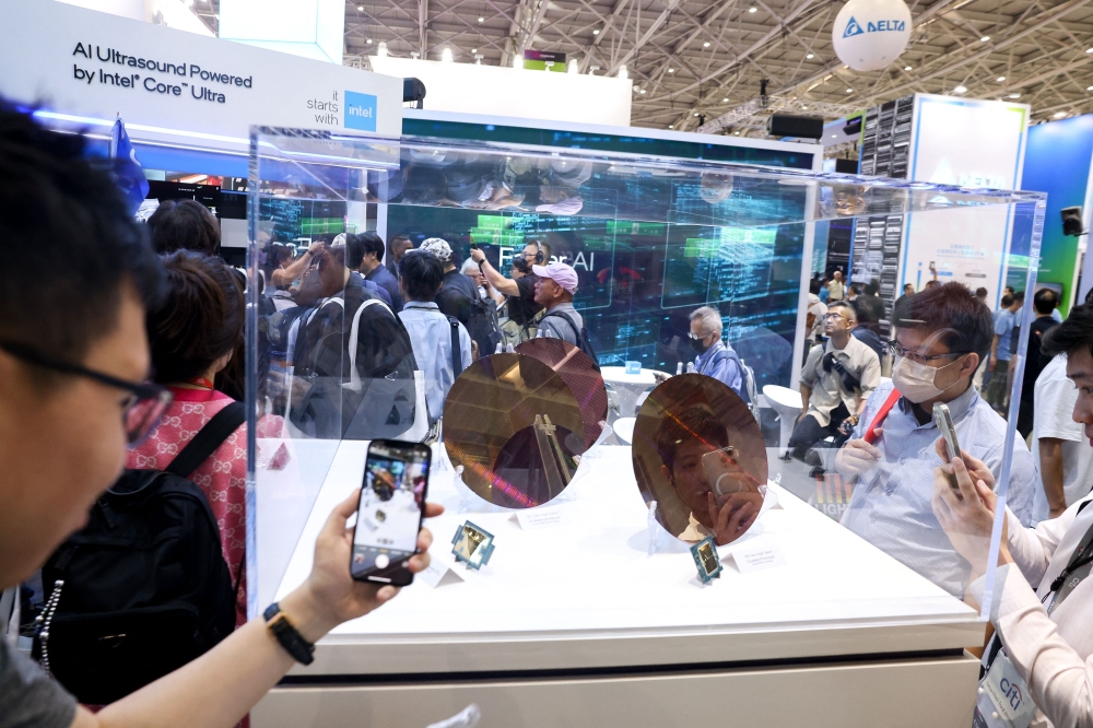 Visitors take pictures of wafer samples at the Intel booth during Computex 2024 in Taipei on June 4, 2024. — AFP pic
