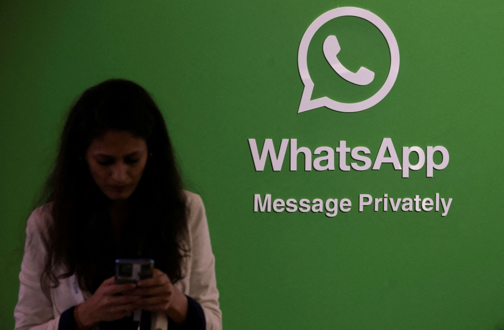 A woman uses her phone next to a logo of the WhatsApp application during Global Fintech Fest in Mumbai, India September 20, 2022. — Reuters pic