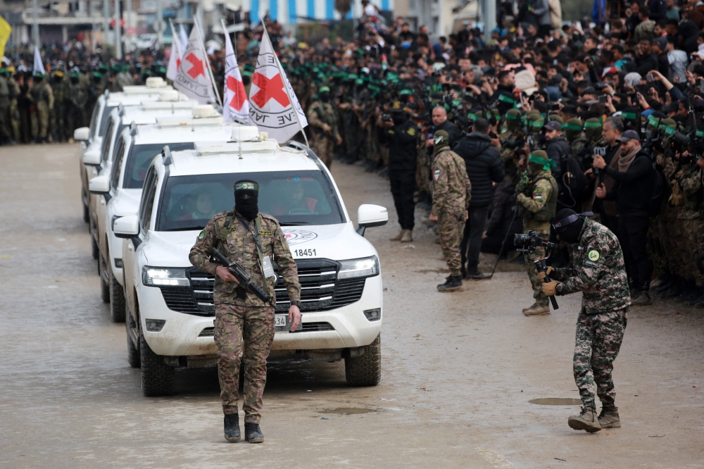 A Palestinian Hamas fighter precedes International Red Cross (ICRC) vehicles as they arrive in Nuseirat in the central Gaza Strip to receive three Israeli hostages as part of the seventh hostage-prisoner swap on February 22, 2025. — AFP pic 