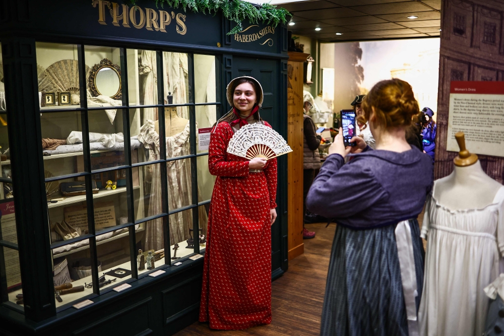 Visitors try on period clothing as they take a tour of the Jane Austen Centre in Bath, Somerset on February 14, 2025. — AFP pic