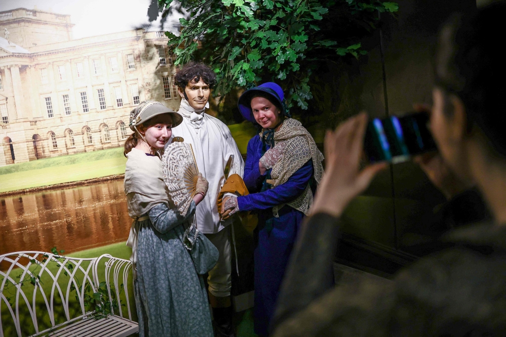 Visitors try on period clothing as they take a tour of the Jane Austen Centre in Bath, Somerset on February 14, 2025. — AFP