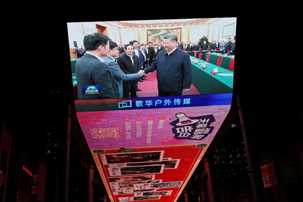 A giant screen shows news footage of Chinese President Xi Jinping shaking hands with DeepSeek founder Liang Wenfeng during a symposium on private enterprises, at a shopping complex in Beijing, China, February 17, 2025. — Reuters pic