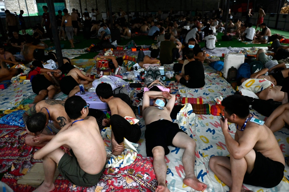 Alleged scam centre workers and victims rest during a crackdown operation by the Karen Border Guard Force (BGF) on illicit activity, at the border checkpoint with Thailand in eastern Myanmar township of Myawaddy township. – Pic by AFP 