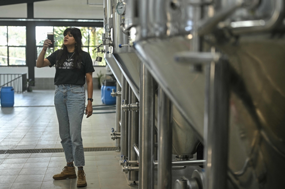 This photograph taken on February 20, 2025 shows Varsha Bhat, a brewer, checking a sample of beer from a tank at a brewery near Whitefield in Bengaluru. — AFP pic 
