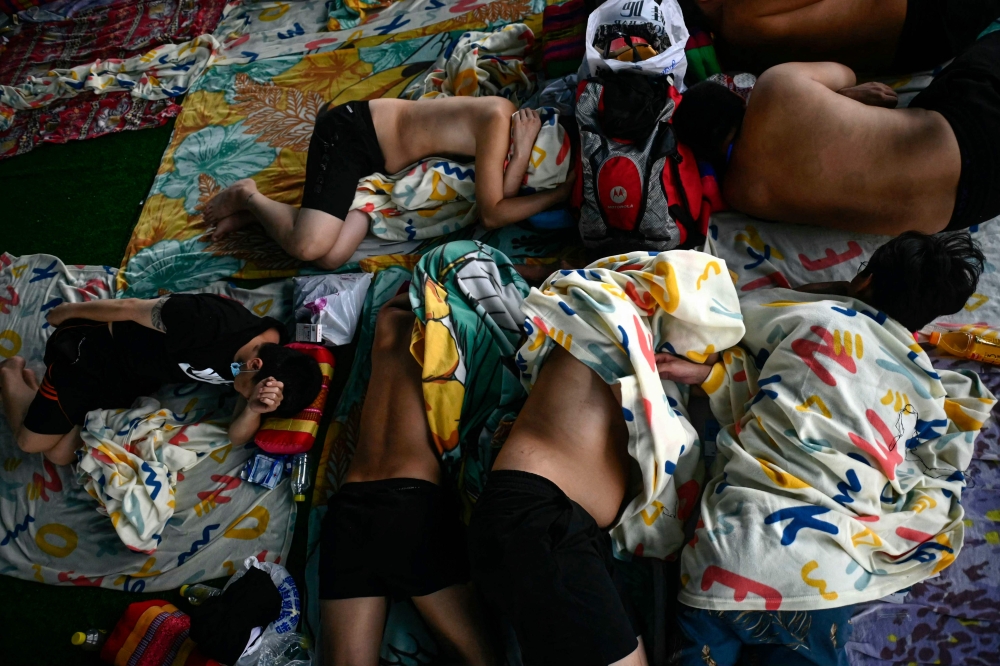 In this photo taken on February 23, 2025 alleged scam centre workers and victims rest during a crackdown operation by the Karen Border Guard Force (BGF) on illicit activity, at the border checkpoint with Thailand in Myanmar's eastern Myawaddy township. — AFP pic